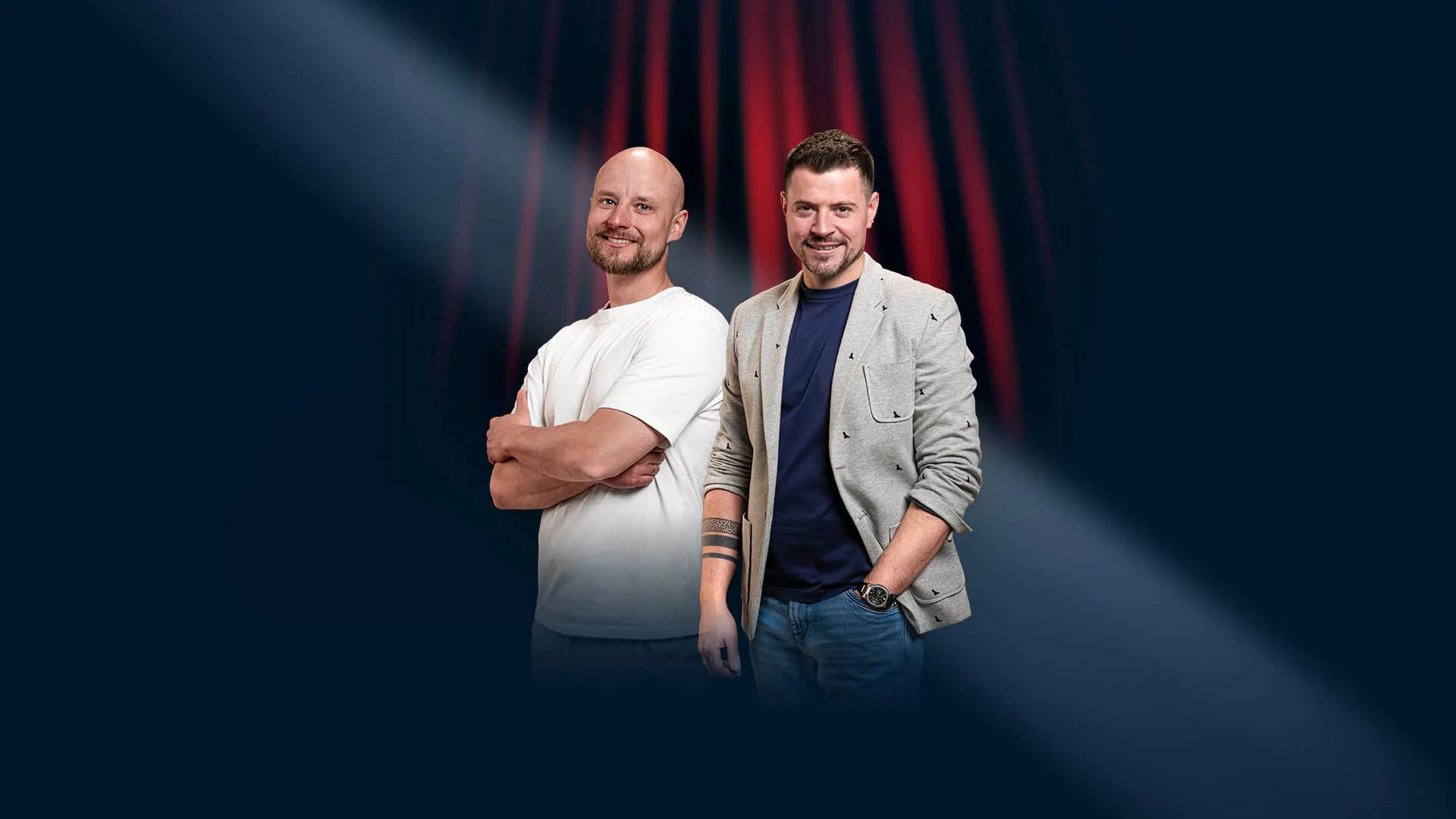 Uśmiechnięci komicy Mateusz Czeklewski i Krzysztof Ofierzyński w świetle reflektorów na tle czerwonej kurtyny, promujący wydarzenie stand-upowe w Klub58.